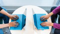 Zwei Menschen tippen auf ihrem Computer