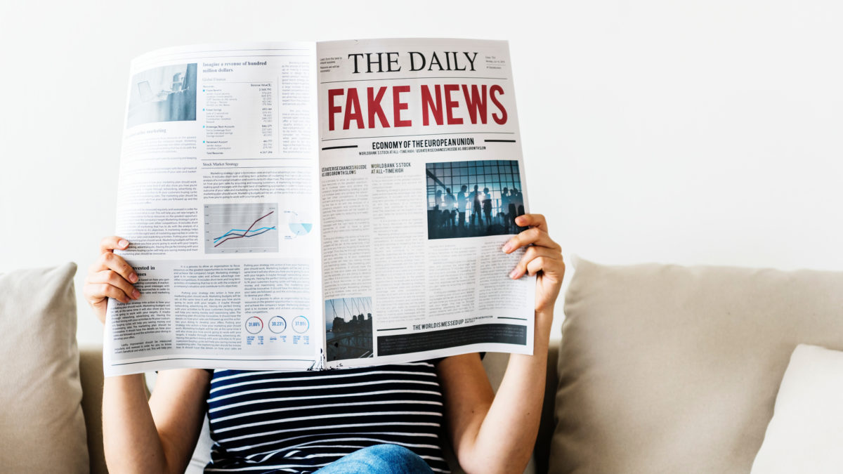 woman reading newspaper with fake news