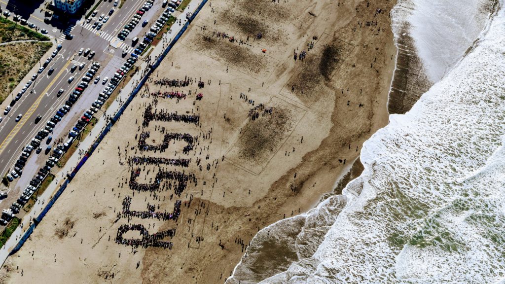 Birds view of "resist" written by people gathering on a beach
