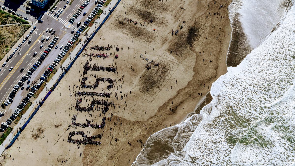 Birds view of "resist" written by people gathering on a beach