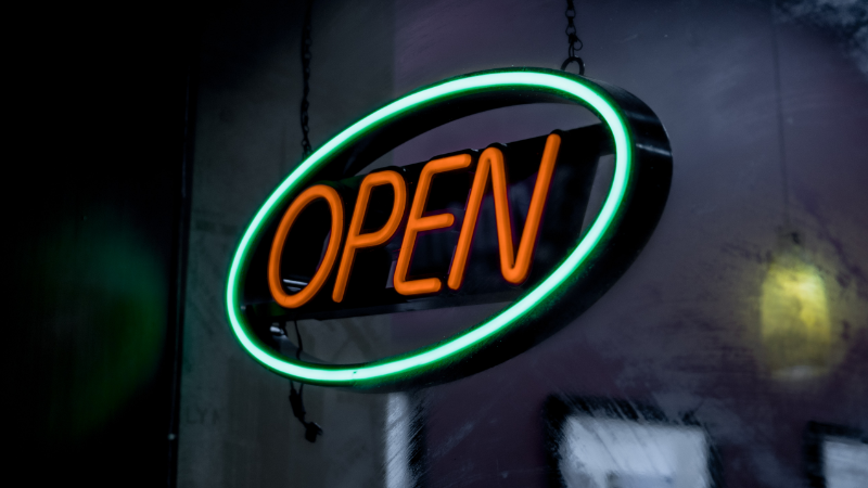 Website_banner_800x450_Job – 2 Titelbild Stellenausschreibung Open!NEXT. Ein Leuchtschild auf dem OPEN steht