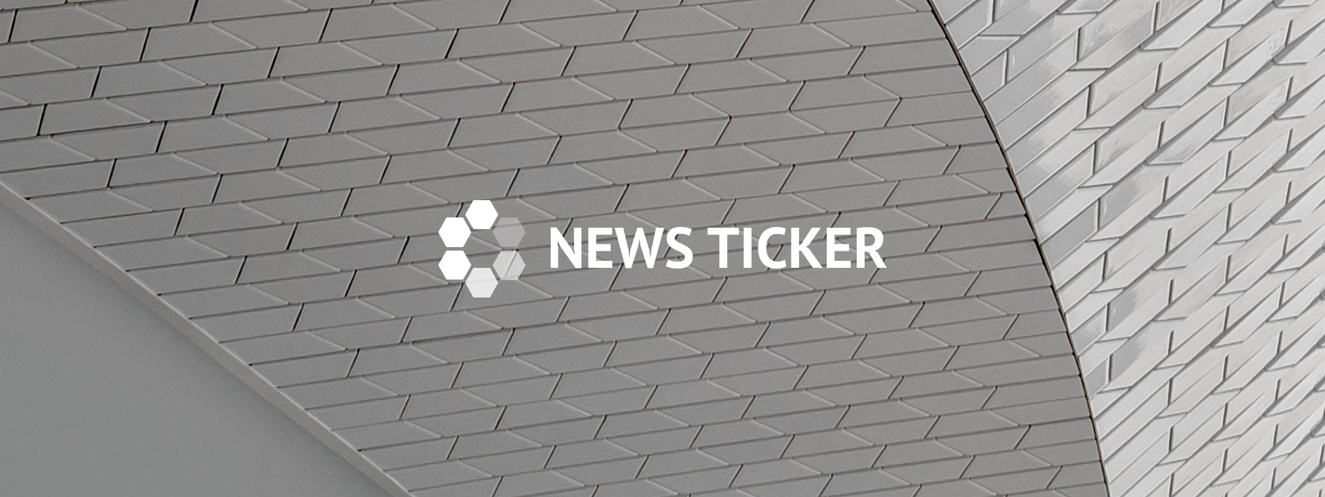 You see a structure of grey bricks and in front of it the word "News Ticker" is written in white.