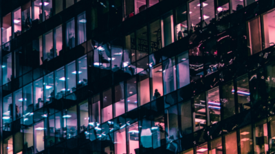 Fassade of a skyscraper with offices. Some of them have blue and purple colored lights on, some are dark, representing the data institute