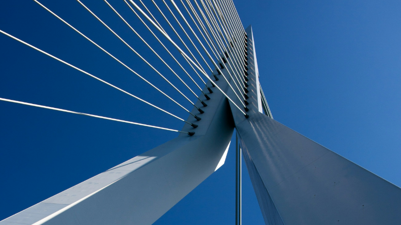 You see a grey steel bridge against a blue sky. It symbolises Examining Freedom of Online Communication Across Transatlantic Borders.