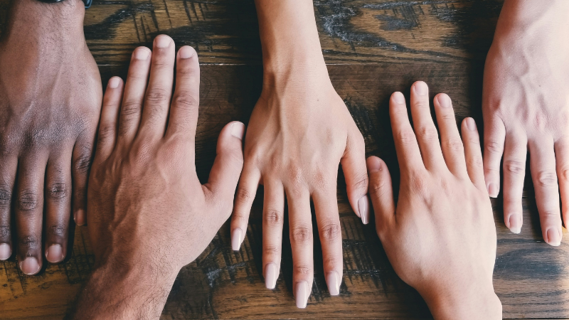Das Foto zeigt Hände nebeneinander. Das symbolisiert die Integration von Geschlecht und Inklusivität in digitale Kulturpolitiken.