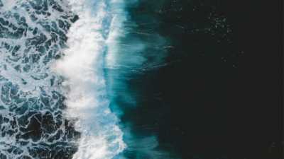 Das Bild zeigt eine hohe Welle, die symbolisch für die Flut an Hassnachrichten gegen Forscher*innen und Anfeindungen in der Wissenschaft.