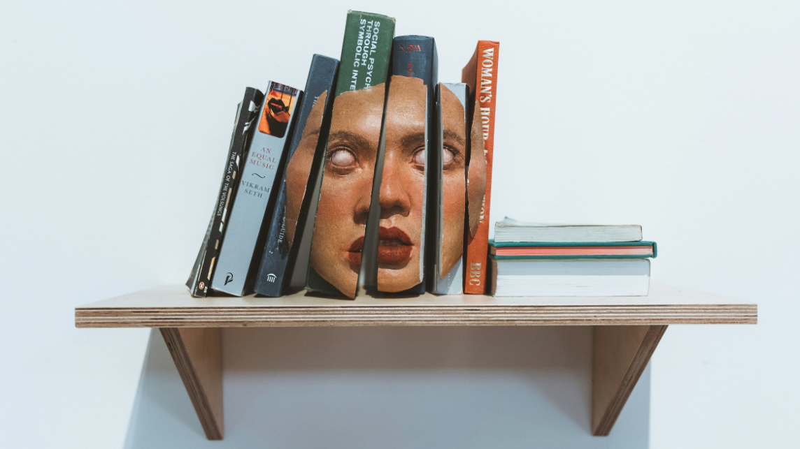 A shelf with books and a deconstructed face sculpture, symbolising how AI and bias influence knowledge and learning in higher education.