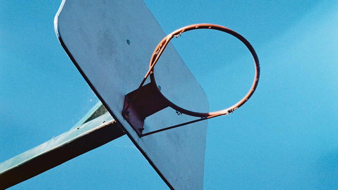 Das Bild zeigt den orangenen Ring eines Basketballkorbs vor blauem Himmel, symbolisch für den Human in the Loop in der Kreditvergabe.