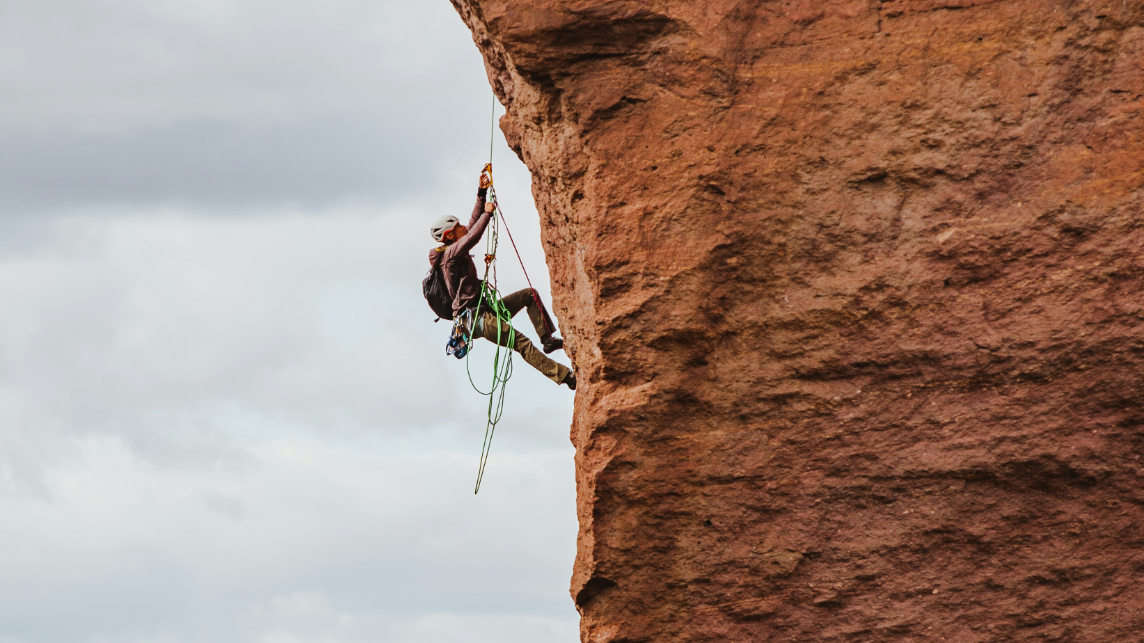 A person climbing a steep rock face, symbolising the effort AI observatories make to scrutinise and challenge the structures of algorithmic power.