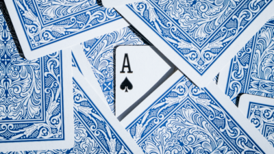 Spielkarten auf einem Tisch mit einem versteckten Ass, als Symbol für das strategische Kräftemessen bei der Regulierung von Online-Plattformen durch den Digital Services Act.