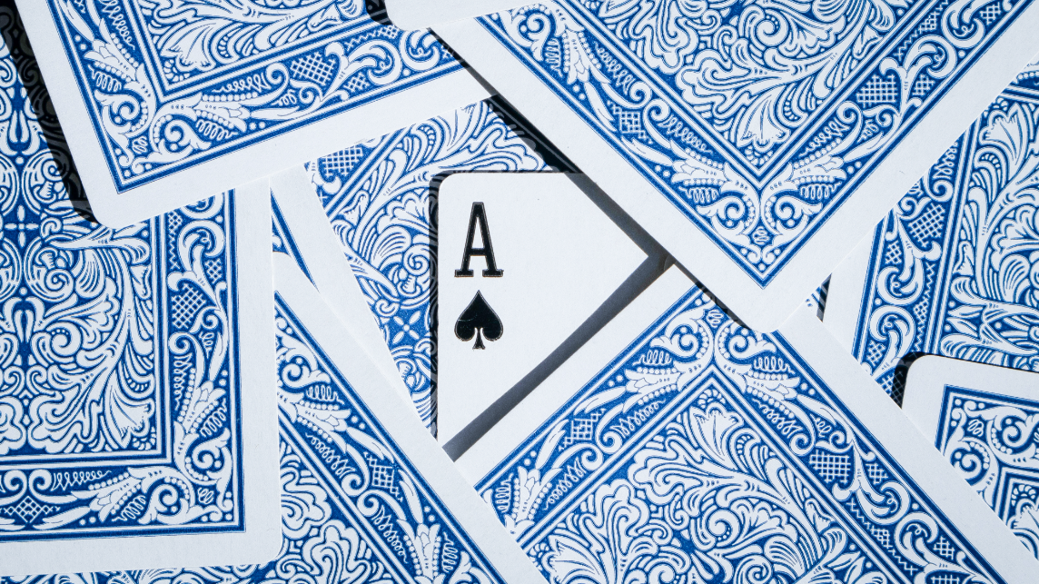 Spielkarten auf einem Tisch mit einem versteckten Ass, als Symbol für das strategische Kräftemessen bei der Regulierung von Online-Plattformen durch den Digital Services Act.