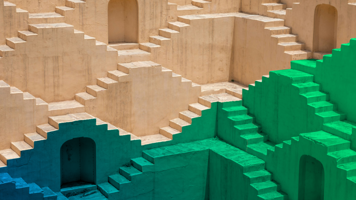 Eine verschachtelte Architektur aus Treppen und Torbögen leuchtet von Sandgelb über Blau bis Grün und symbolisiert die Hürden von KI-Unternehmer*innen und die Zukunft zur besseren Förderung.