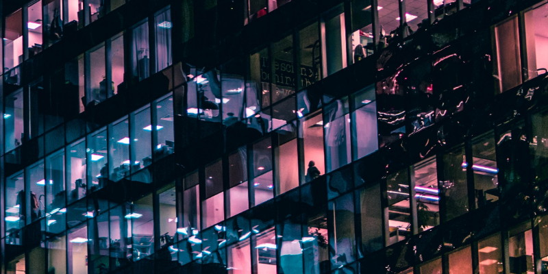 Fassade of a skyscraper with offices. Some of them have blue and purple colored lights on, some are dark, representing the data institute