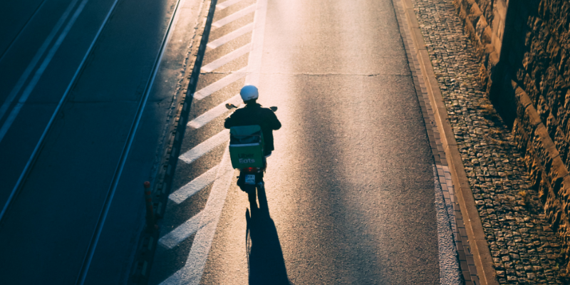 Man sieht eine*n Lieferant*in eines Online-Lieferdienst für Essen auf einem Motorroller. Das Bild steht sinnbildlich für die Arbeitenden in der Gig Economy in Kenia. You see a delivery person from an online food delivery service on a scooter. The image is emblematic of the workers in the gig economy in Kenya. 