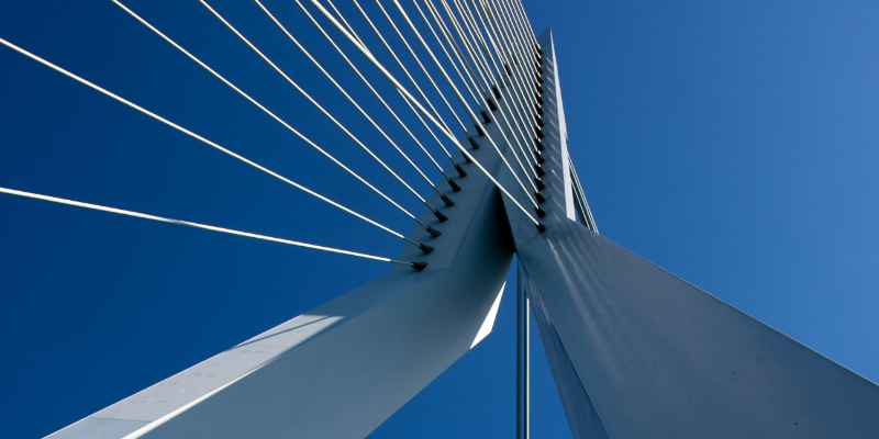 You see a grey steel bridge against a blue sky. It symbolises Examining Freedom of Online Communication Across Transatlantic Borders.