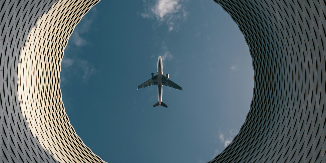 LuftfahrtBlog The photo shows an airplane seen from below flying over a circular building. This symbolizes the human role alongside the autopilot in aviation.
