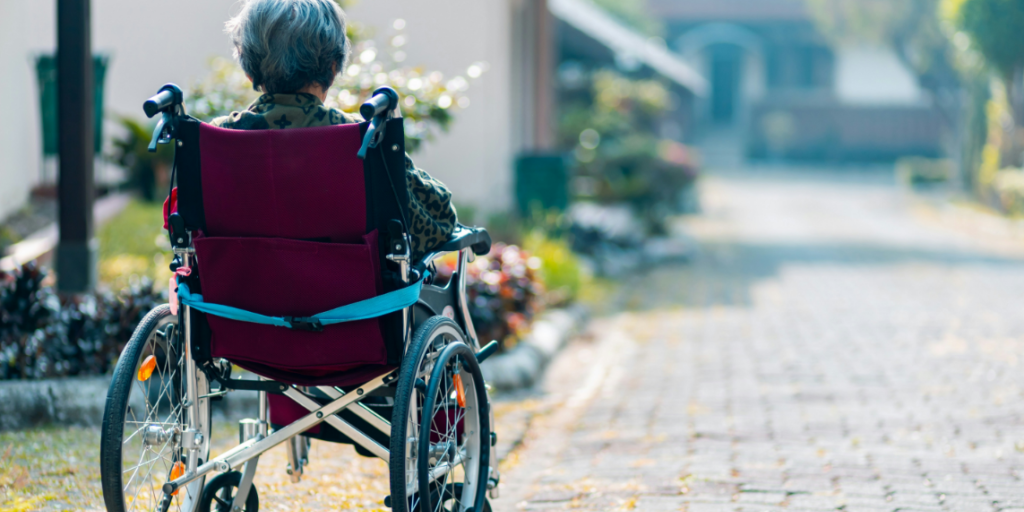 An older woman in a wheelchair sitting alone. This reflects the urgent need to combat loneliness through digital tools and community-based, inclusive care facilities.