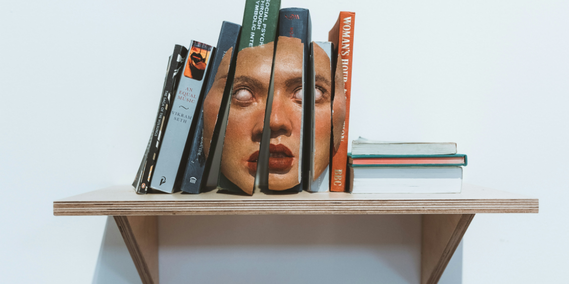 A shelf with books and a deconstructed face sculpture, symbolising how AI and bias influence knowledge and learning in higher education.