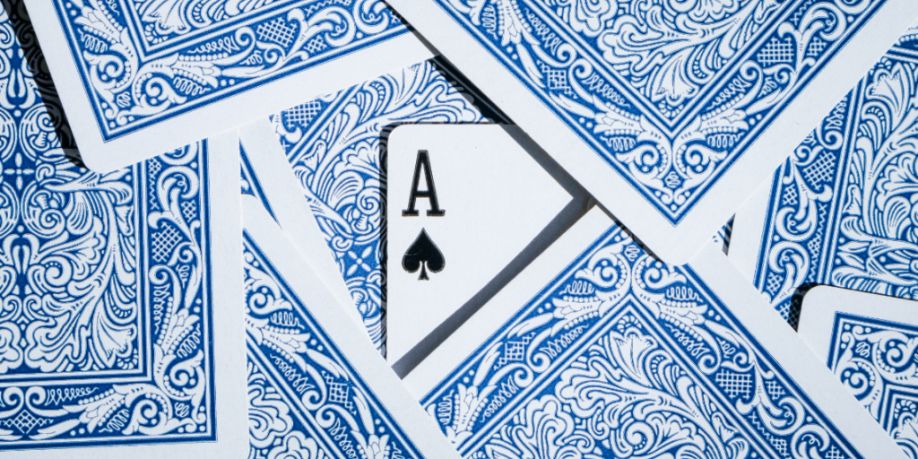 Titelbild_DanielDSA1 Spielkarten auf einem Tisch mit einem versteckten Ass, als Symbol für das strategische Kräftemessen bei der Regulierung von Online-Plattformen durch den Digital Services Act.