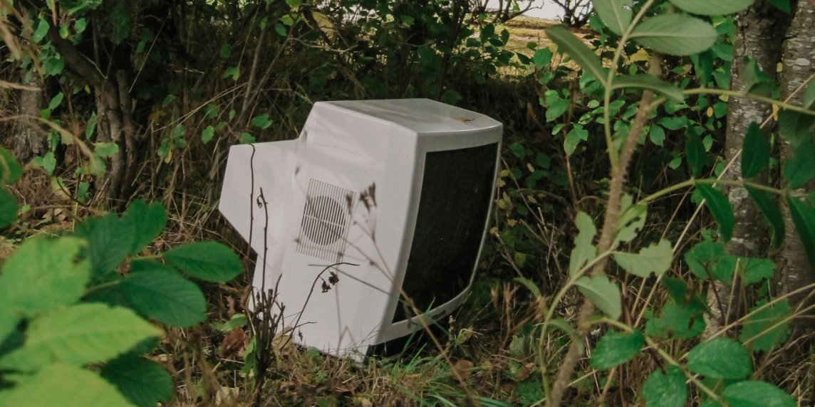 Titelbild_Stoffwechsel The photo shows an old television set standing in the middle of a forest, symbolising the hidden environmental cost of digital technology and the concept of the digital metabolic rift.