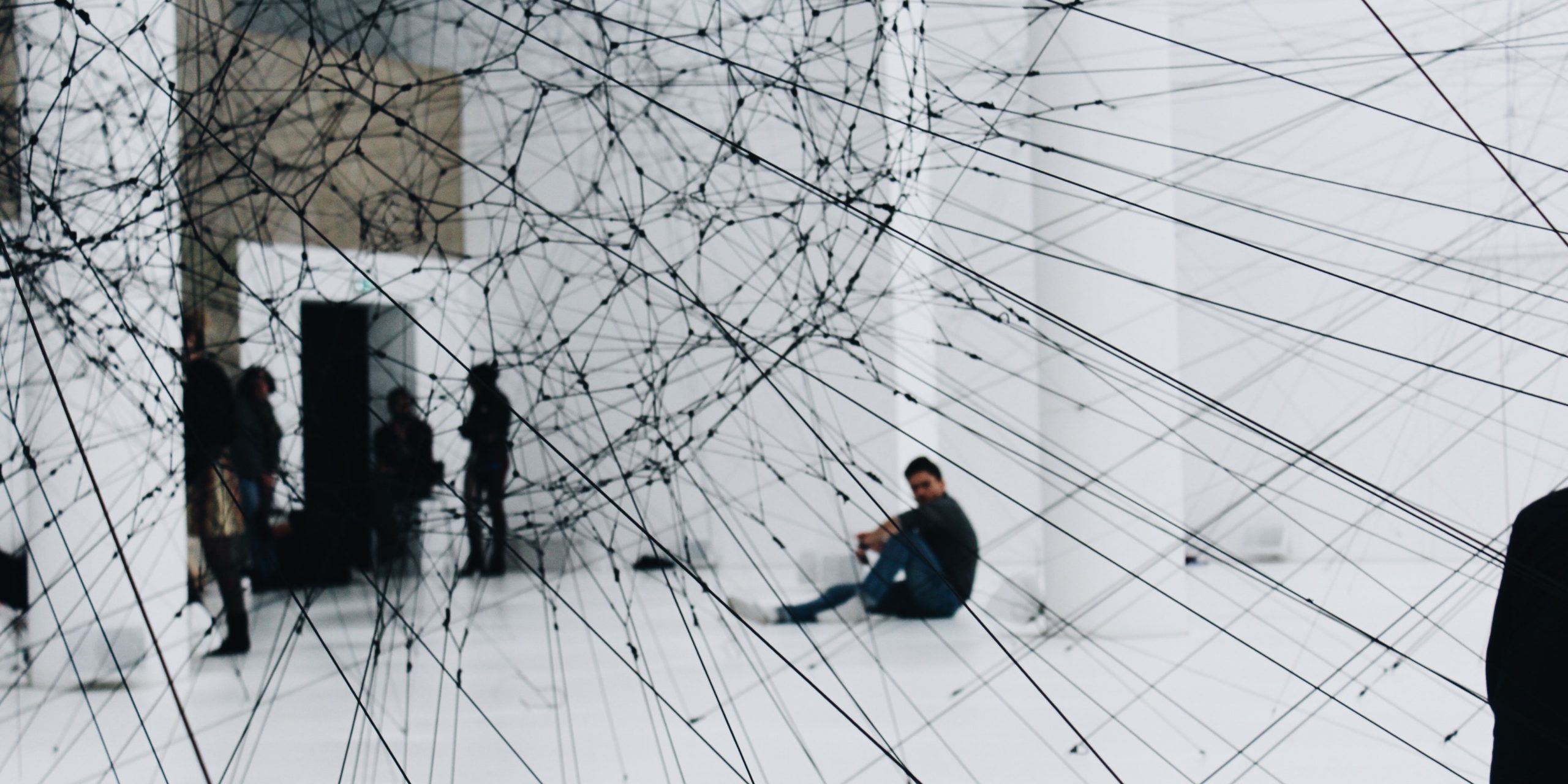People standing behind a web of strings