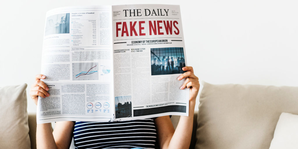 woman reading newspaper with fake news