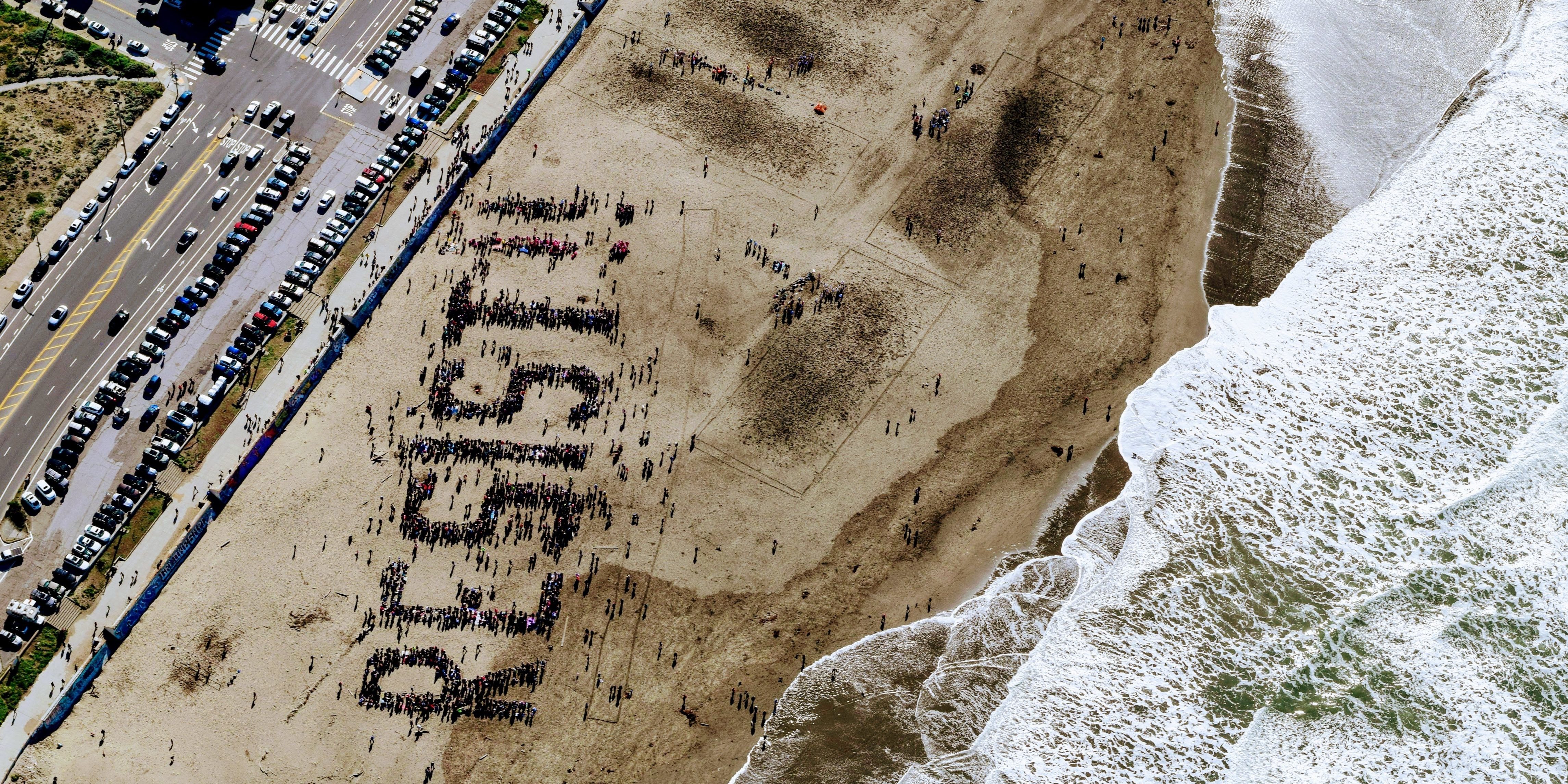 Birds view of "resist" written by people gathering on a beach